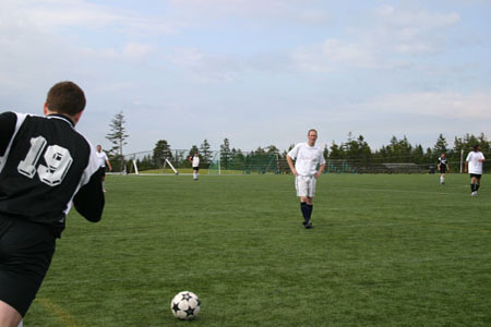 Metro Uniteds Jake Harris takes a free kick while Alumitech's Richard Haussman looks on